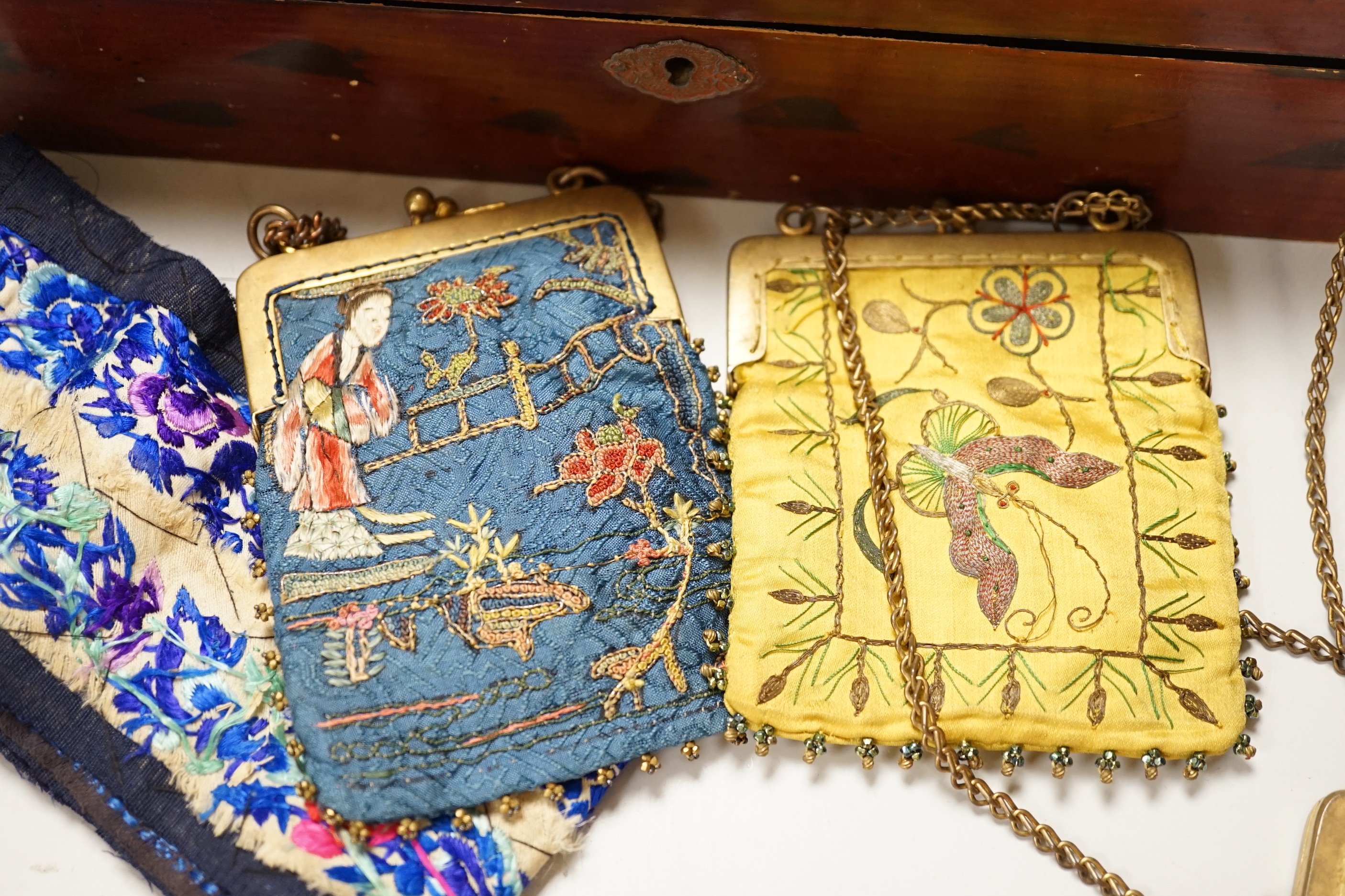 A lacquer box of Chinese embroidered purses and embroideries.